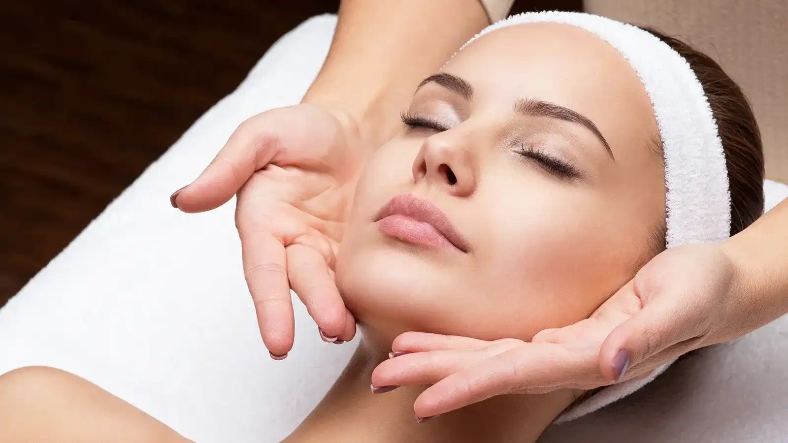 Relaxing facial treatment with closed eyes and headband.