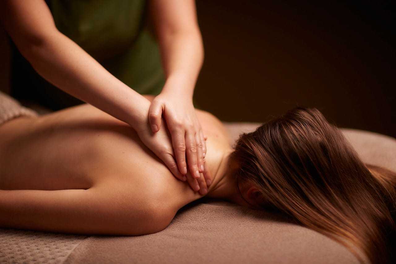 Massage therapist giving a relaxing back massage to a woman in a spa setting.