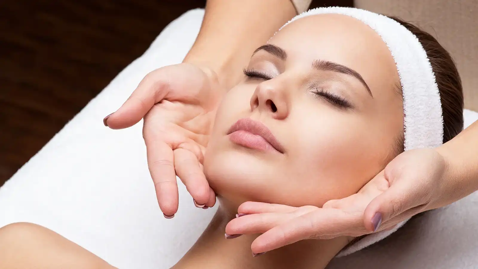 Relaxing facial treatment with closed eyes and headband.